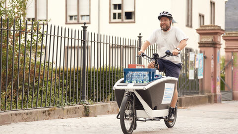 Radfahrer auf Nahmobilität-Lastenrad mit Wasserkästen