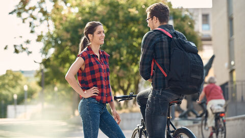 Frau steht vor Mann auf Fahrrad