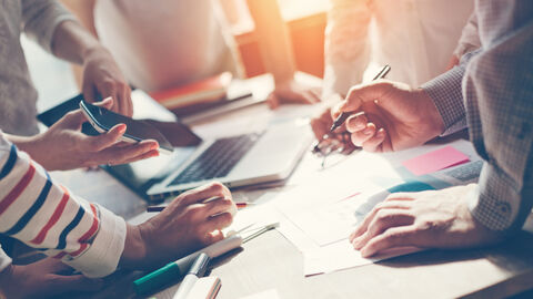 Viele Hände arbeiten an einem Tisch gemeinsam an einem Projekt