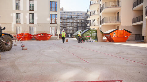 Bauarbeiter im Innenhof einer Neubausiedlung im Rohbau
