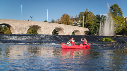 Zwei Personen paddeln auf der Lahn in einem roten Kanu
