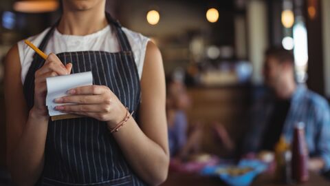 Bedienung in einem Restaurant notiert etwas auf einen Block