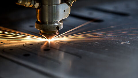Metall wird mit Laser geschnitten, dabei fliegen Funken