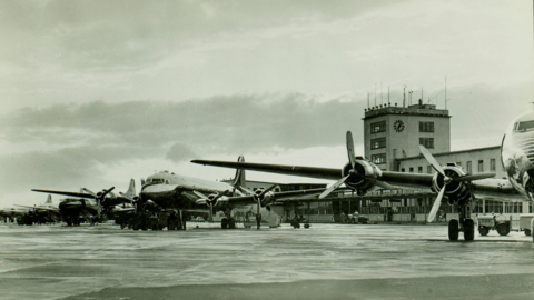 Flugzeuge aufgereiht vor Flughafengebäude 1955