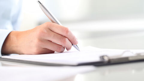 Nahaufnahme einer Hand, die ein Formular ausfüllt