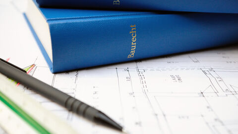 Bücher mit dem Titel Baurecht liegen auf einem Architekturplan