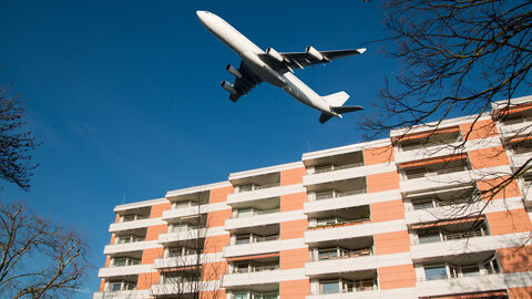 Flugzeug fliegt nah über Wohngebäude