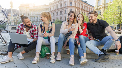 Freunde sitzen vor Brunnen zusammen und lachen