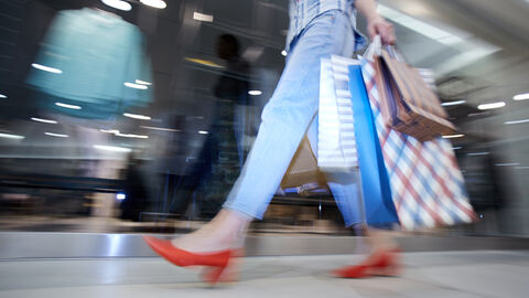 Frau läuft mit Einkaufstüten an Schaufenster vorbei