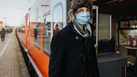 Frau mit Maske steigt in den Zug ein
