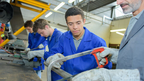 Auszubildender lernt wie man eine Metallstange durchschneidet