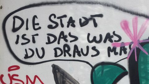 Bunter Grafitti-Spruch auf Hauswand. Die Stadt ist das, was du draus machst