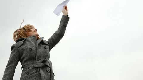 Eine Frau lässt einen Papierflieger fliegen