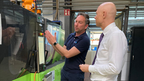 Staatssekretär Nimmermann lässt sich bei Kunsstofftechnik BURK an der Maschine etwas zeigen.