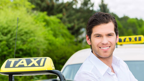 Fahrer lehnt an einem Taxi