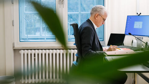 Minister sitzt am Schreibtisch und liest Akten