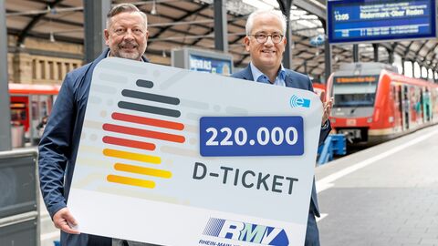 Tarek Al-Wazir und Knut Ringat (RMV) halten großes Plakat mit Deutschlandticket am Wiesbadener Hauptbahnhof