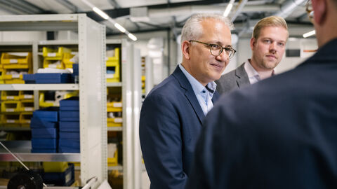 Besuch beim Elektromotorenhersteller Plettenberg Al-Wazir im Gespräch mit weiteren Personen in einer Halle von Plettenberg.