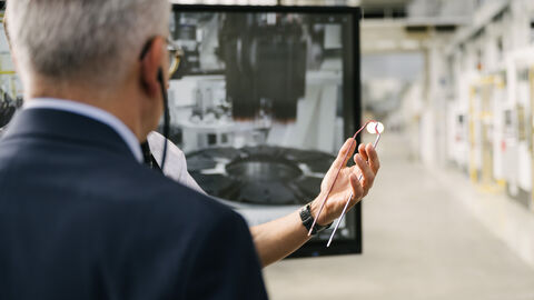 Eine Hand hält ein Metallteil vor Wirtschaftsminister Al-Wazir. Dieser ist der Hand zugewandt.