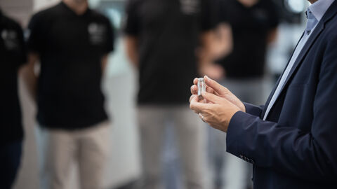 Nahaufnahme von Händen, die eine kleine Glasphiole halten.