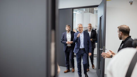 Wirtschaftsminister Al-Wazir betritt einen Raum durch eine Tür, ihm folgen zwei weitere Personen.