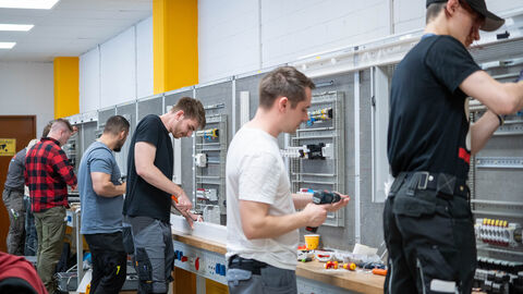 Mehrere Männer stehen an einer Wand mit Elektrostecktafeln 