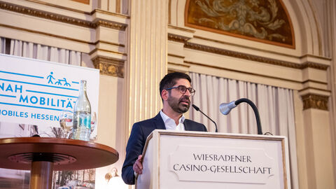 Ein Mann steht an einem Stehpult und spricht in ein Mikro