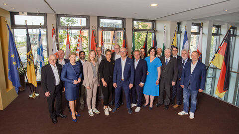 Mehrere Personen stehen vor verschiedenen Flaggen