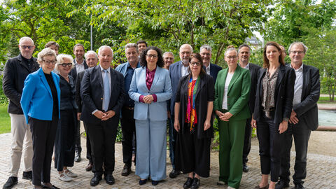 Mehrere Personen stehen im freien vor einem Baum