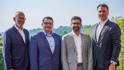 Vier Männer stehen auf einem Balkon