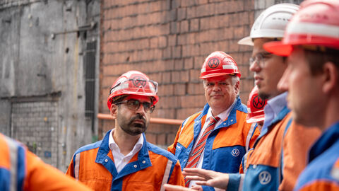 Mehrere Personen tragen Helme und orangene Jacken