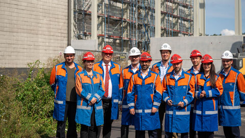 Mehrere Personen tragen Helme und orangene Jacken