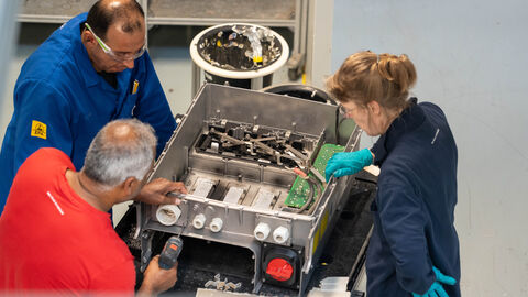 Drei Personen arbeiten an einem technischen Gerät