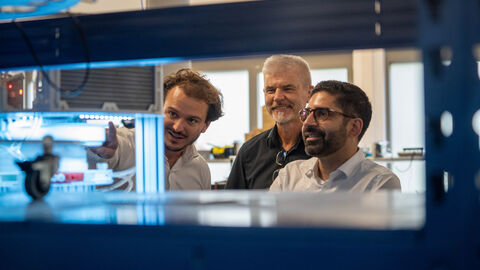 Drei Männer betrachten eine Kühlanlage