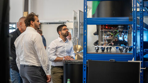 Drei Männer betrachten ein technisches Objekt