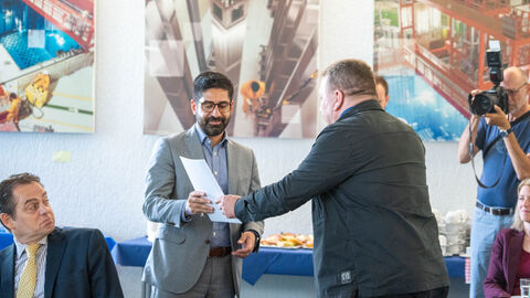 Ein Mann überreicht einem anderen einen Umschlag