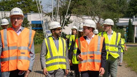 Mehrere Personen in Warnwesten laufen über ein Industriegelände