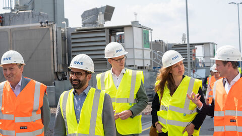 Mehrere Personen in gelben Warnwesten laufen über ein Industriegelände