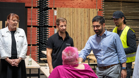 Ein Mann schüttelt einer Frau im Rollstuhl die Hand