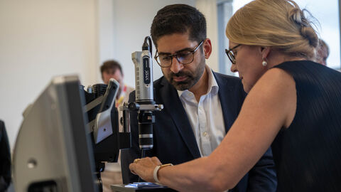 Ein Mann und eine Frau stehen an einem Mikroskop