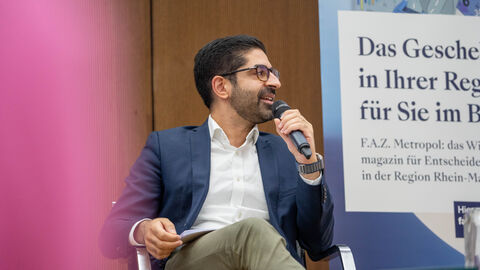 Ein Mann sitzt mit einem Mikrofon auf der Bühne