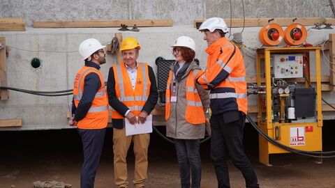 Vier Personen in Warnwesten stehen vor einem Brückenbauwerk