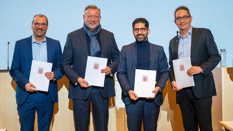 Vier Männer halten Mappen mit dem Hessen Wappen in der Hand