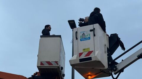 Mehrere Personen auf Hubwagen an einer Straßenlaterne