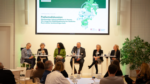 Mehrere Personen sitzen auf einem Podium