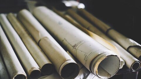 zusammengerollte, alte Baupläne übereinander gestapelt