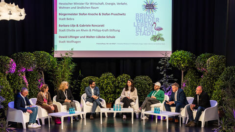 Mehrere Personen sitzen auf einer Bühne