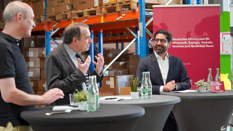 Drei Männer stehen an Stehtischen