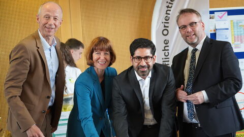 Vier Personen stehen an einem Tisch und unterzeichnen einen Vertrag