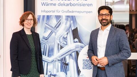 Zwei Personen stehen vor einem Banner 